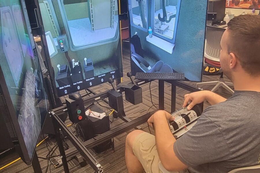 An individual operates a crane training simulator in the CIVS visualization lab