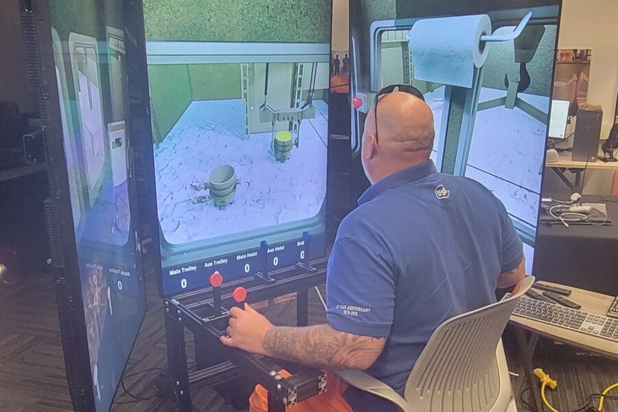 An individual in a work uniform operates a crane training simulator in the CIVS visualization lab