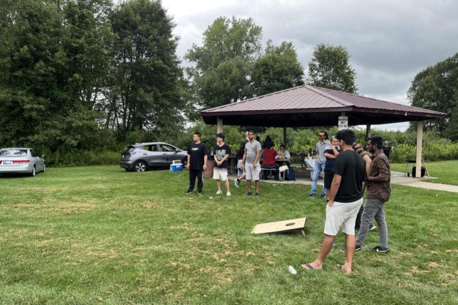 Individuals playing a game in a park with others standing and watching