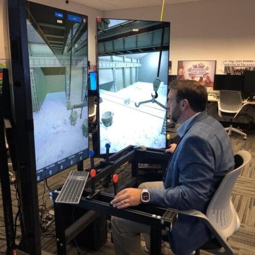 An individual in business professional attire operates a crane training simulator in the CIVS visualization lab