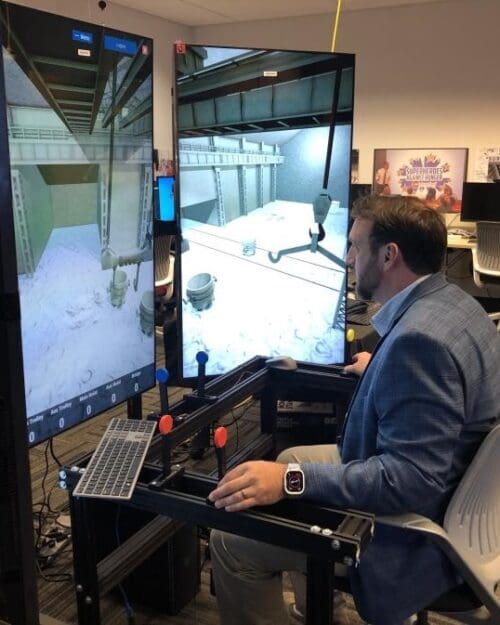 An individual in business professional attire operates a crane training simulator in the CIVS visualization lab