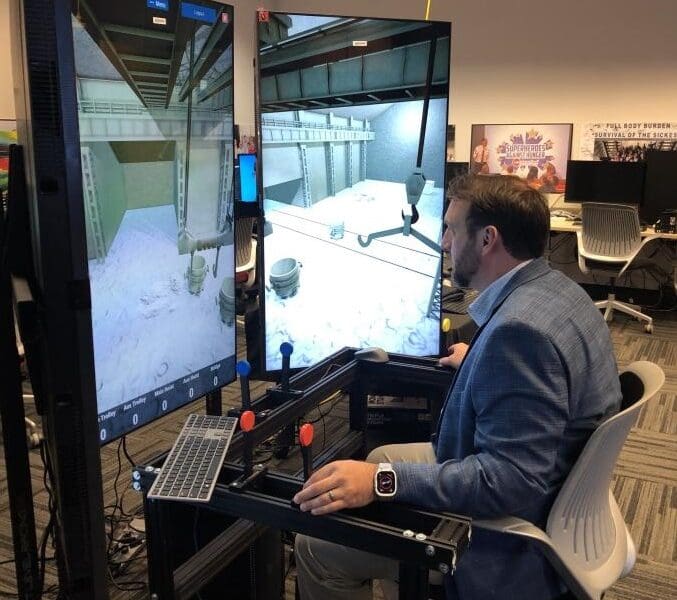 An individual in business professional attire operates a crane training simulator in the CIVS visualization lab