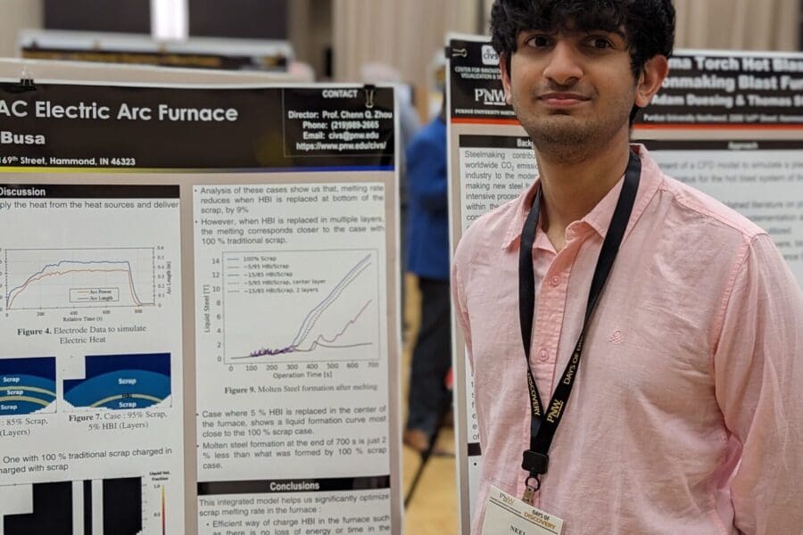 Young student in a casual business attire standing in front of academic poster in presentation hall