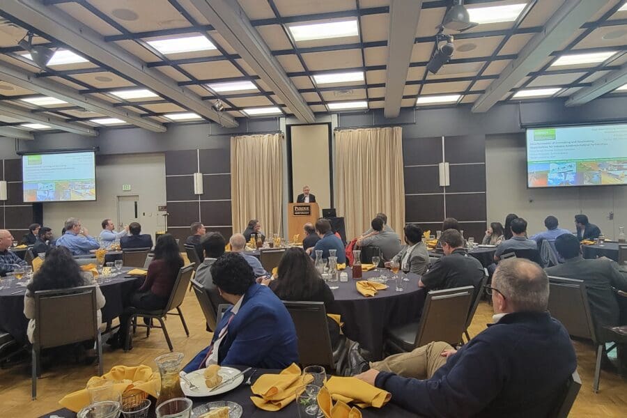 Man standing at podium in front of guests seated at several round tables