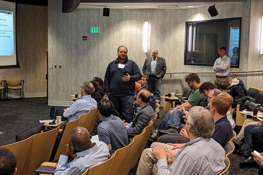 Man standing and talking in an auditorium between rows of seated guests