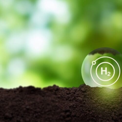 Digital image of nature featuring loose dirt, a green background and a water droplet superimposed with the logo for Hydrogen (h2)