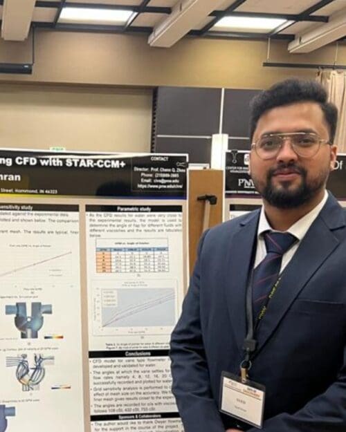 Young student in a navy suit standing in front of academic poster in presentation hall