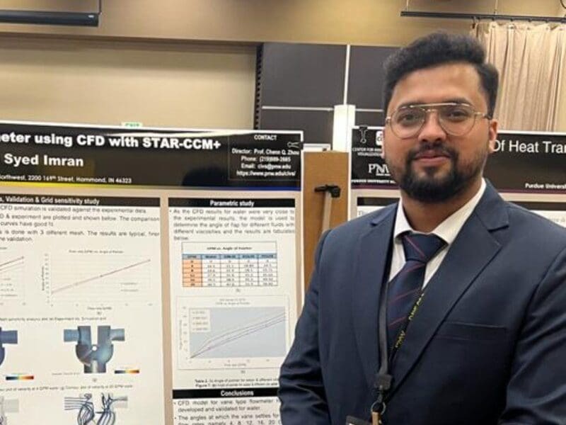 Young student in a navy suit standing in front of academic poster in presentation hall