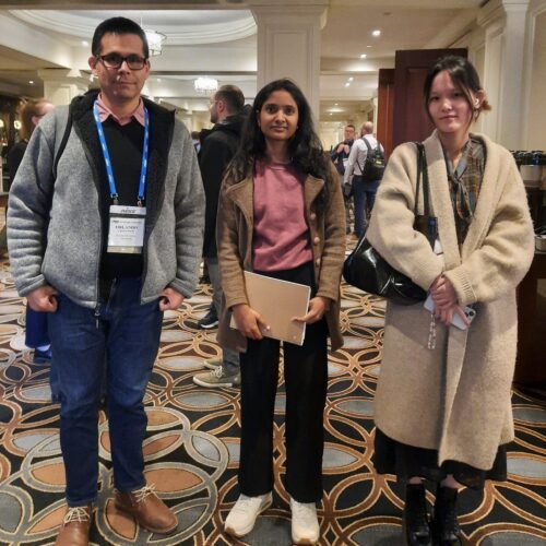 CIVS researchers Orlando Ugarte, Sathvika Kottapalli, and Shiyu Wang standing in a hallway of a convention center wearing special passes on lanyards