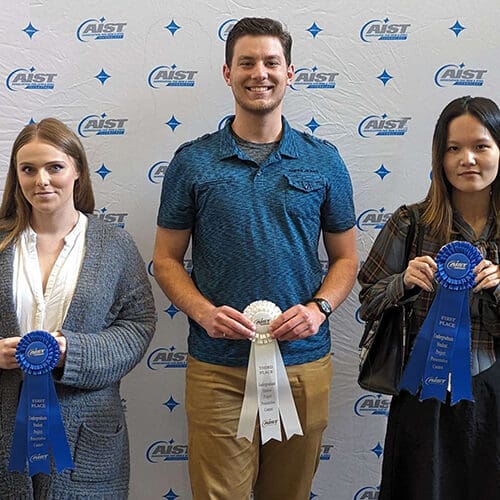 Three students pose with ribbons