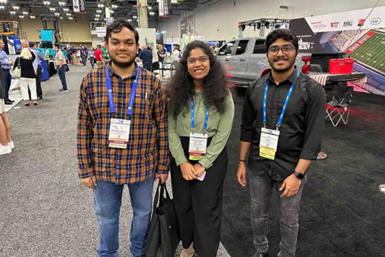 Three students stand together wearing badges