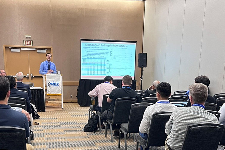 A person stands at a podium and gives a presentation to a room of people