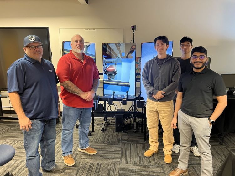2 U.S. Steel Reps standing with 3 CIVS staff in front of crane simulator