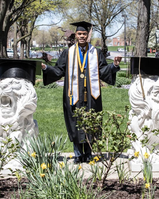 Student posing outside next to lion statues at graduation