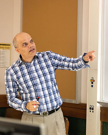 A professor points to a white board