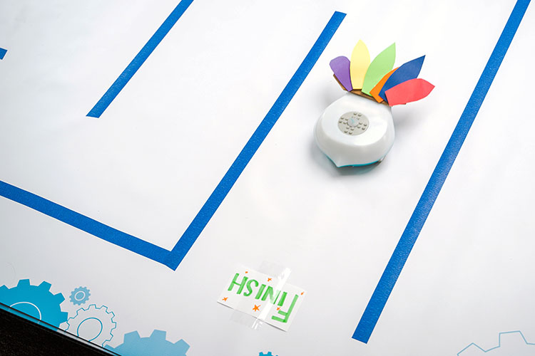 A Finch robot with paper feathers navigates through a maze