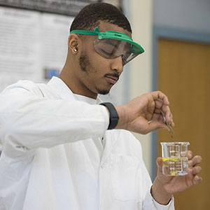 A student in a lab coat works with chemicals