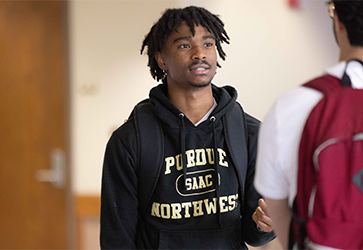 A student in a black hoodie talks to a student off camera