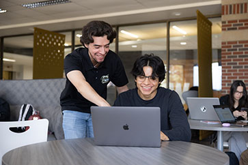 Two students look at a laptop