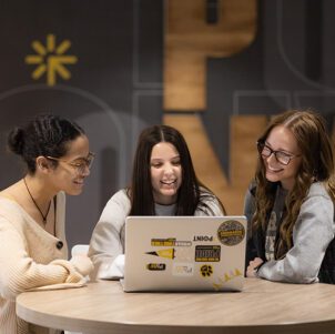 Three students sit around a table in the PNW Mane Zone