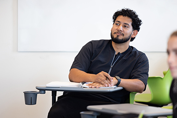 A student sits at a desk in a classroom.