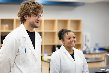 Two students stand in a microbiology lab