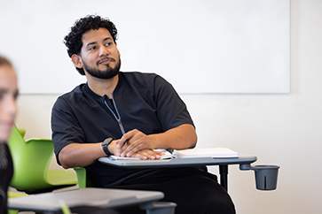 A student in a black t-shirt sits in a classroom.