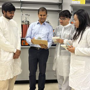 Three students stand with Professor Veera Gnaneswar Gude in a lab space.