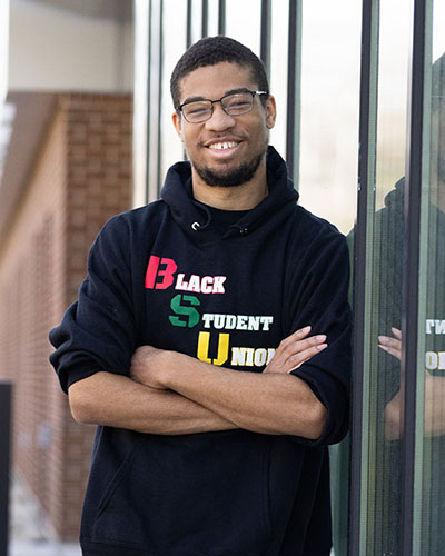 A PNW student stands outdoors in a Black Student Union hoodie