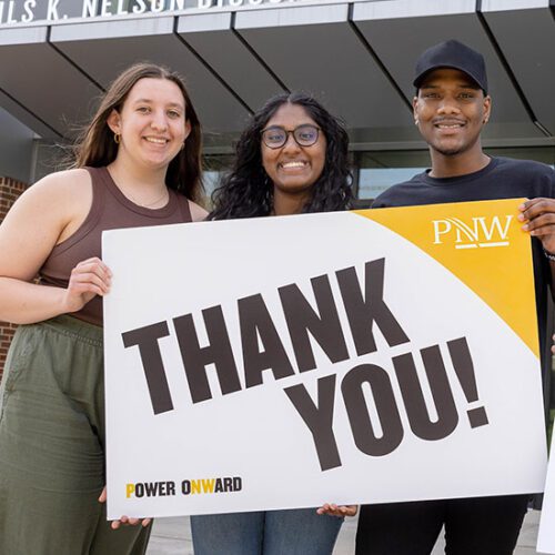 PNW students holding a "thank you" sign in front of the Nils K. Nelson Bioscience Innovation Building