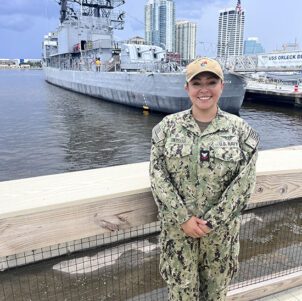 Alyssa Gomezdelacasa stands in uniform in front of a port