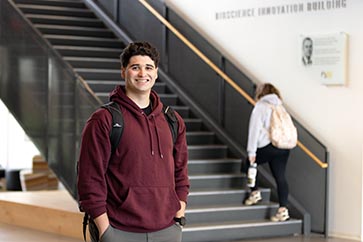 A PNW student stands in front of a stairwell