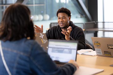 Two students talking with one another in the NILS building 363x242