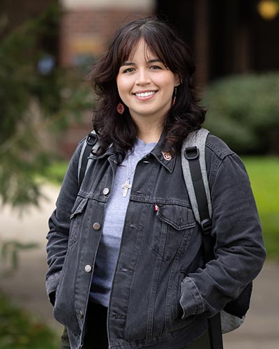 A PNW student stands outdoors in a jacket
