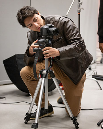 A CHESS Student poses a camera on a tripod.