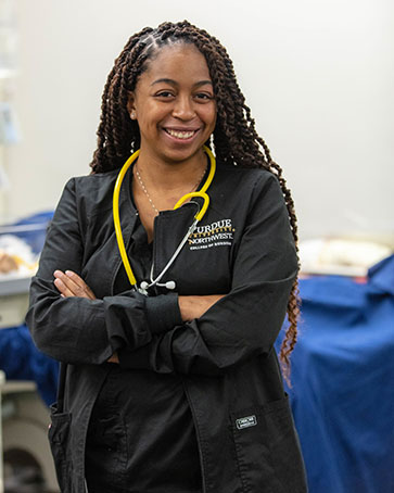 Student stands in scrubs, there is a yellow stethoscope around her neck