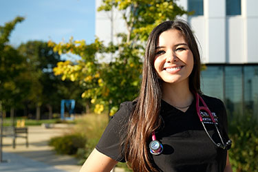 A nursing student outdoors in front of the Nils K. Nelson Bioscience Innovation Building