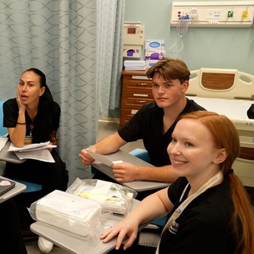Three nursing students sit in a lab room