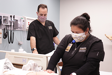 Two students taking care of a mannequin in nursing