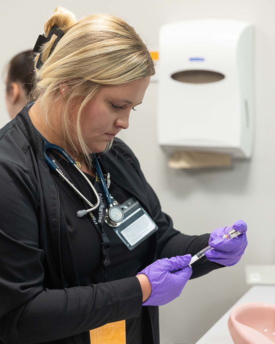 A nursing student drawing a syringe in a lab.