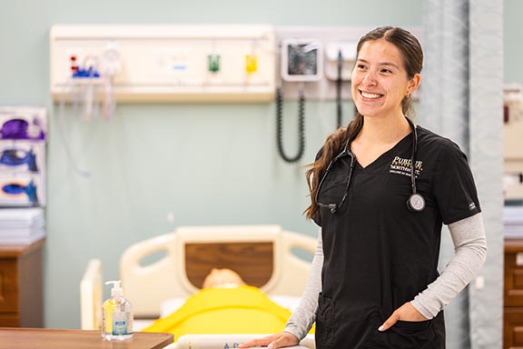 PNW Nursing student standing next to a table in the Nursing Lab.