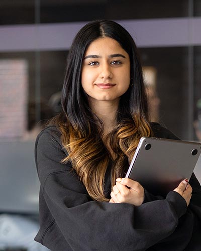 A PNW student holds books indoors