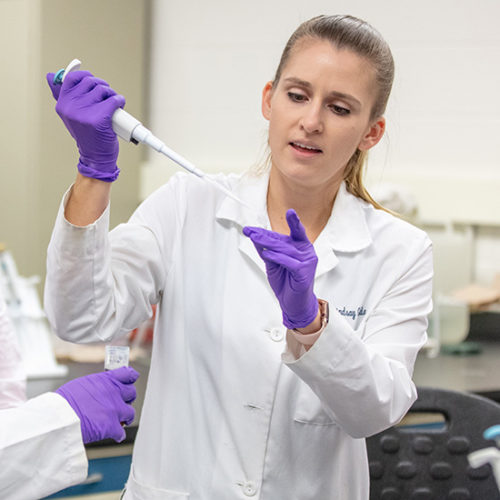 Professor Lindsey Gielda works with students in a lab.