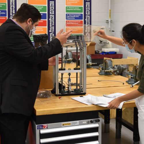 Afshin Zahraee, assistant professor, Mechanical Engineering Technology (left) and Ran Zhou, assistant professor of Mechanical Engineering examine a miniature tensile testing machine for 3D printed parts and specimen for potential use in Remote Knowledge Labs.