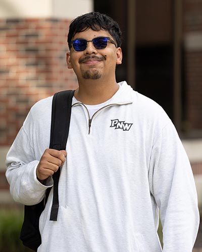 A PNW student outdoors with sunglasses and a backpack.