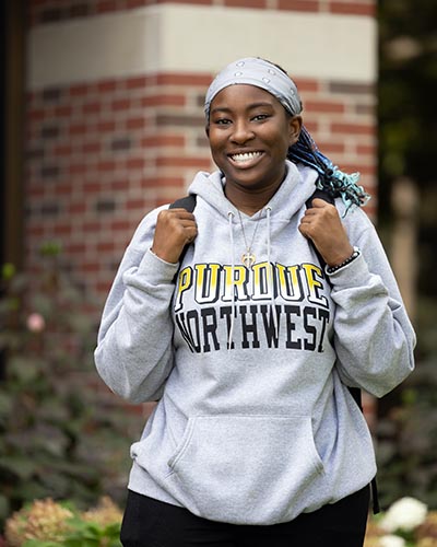 A student in a Purdue Northwest sweatshirt stands outdoors.
