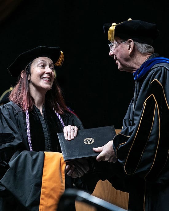 A student receives her diploma from Chancellor Keon