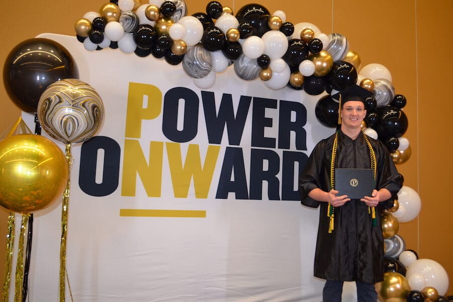 A student pictured in front of Power Onward sign.