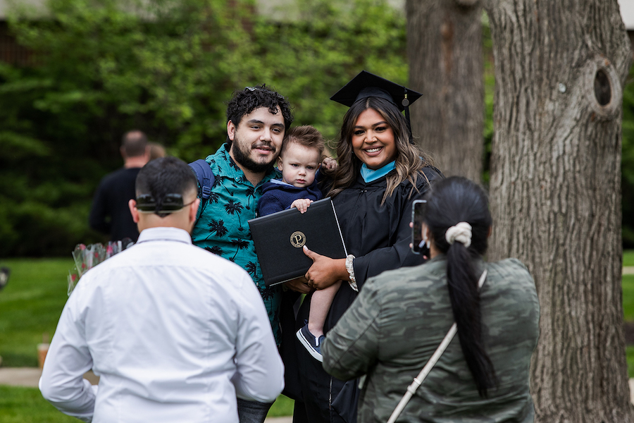 A graduate poses with her baby.