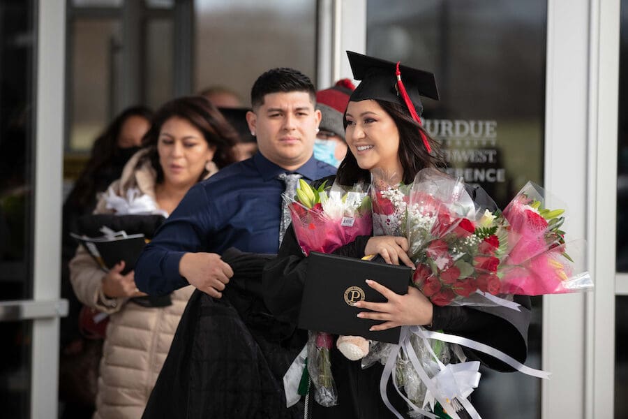 Graduates leave the ceremony carrying flowers.